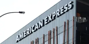 AMERICAN EXPRESS sign in white letters on a modern gray building, with a street light.