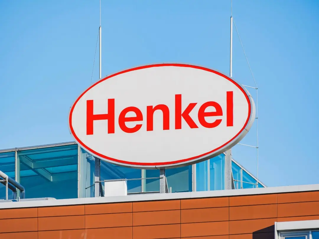 Henkel logo sign on a building against a clear blue sky.