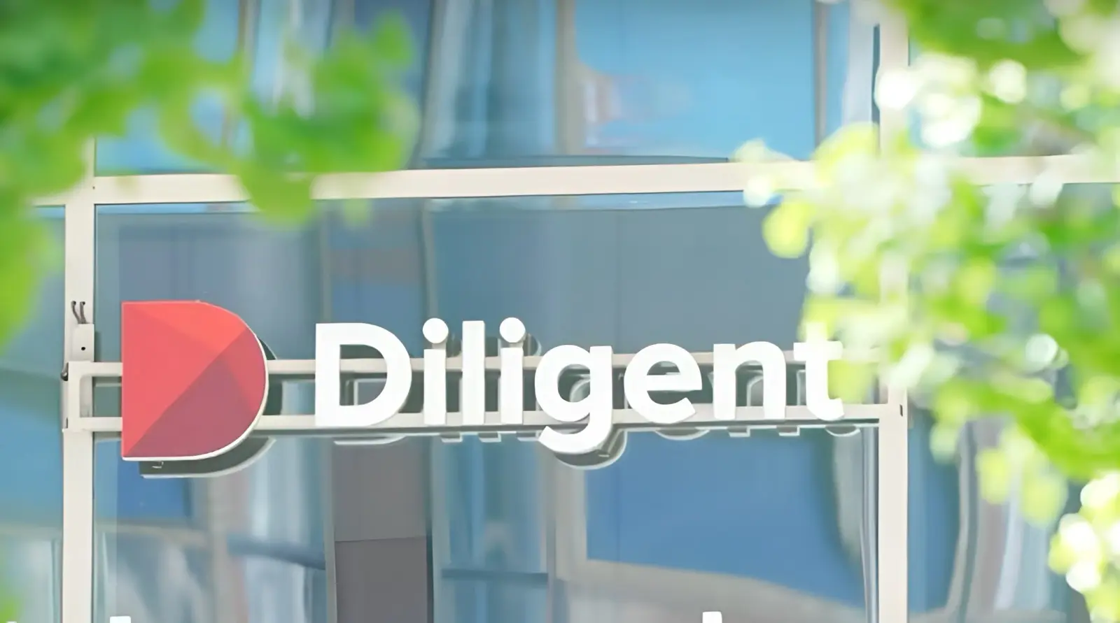 Diligent company name and red D logo on a glass building, with blurred green leaves in the foreground.